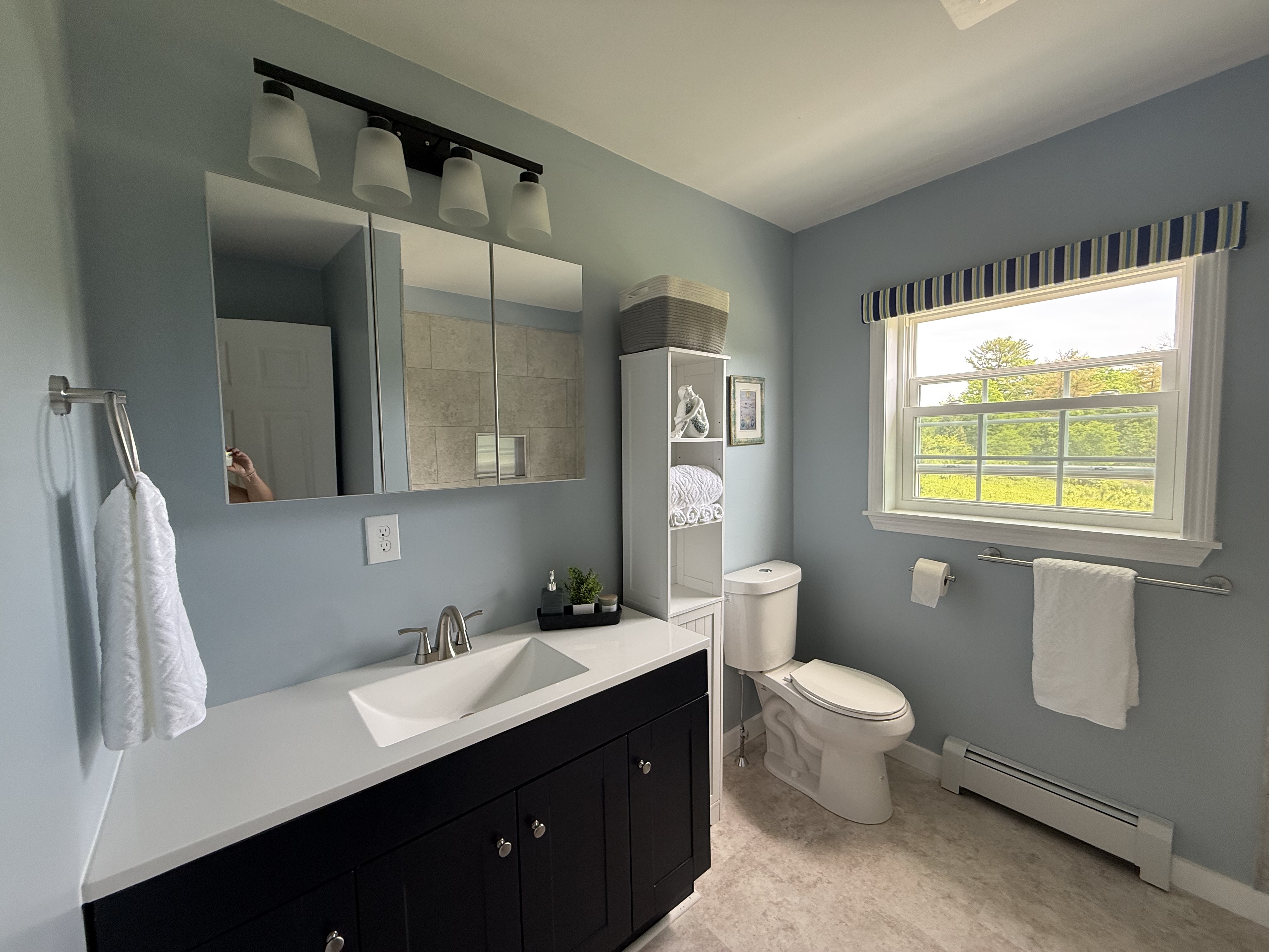 Updated full bathroom with a dark vanity, quartz counter, and soft blue walls